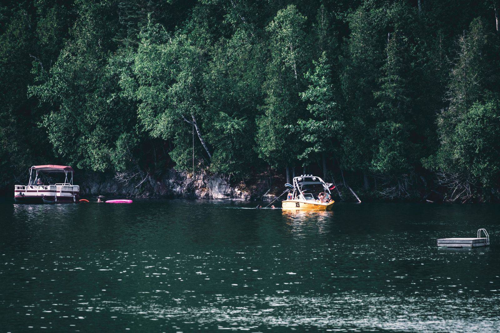 A cottage dock and small boat on a calm Kawartha lake in summer