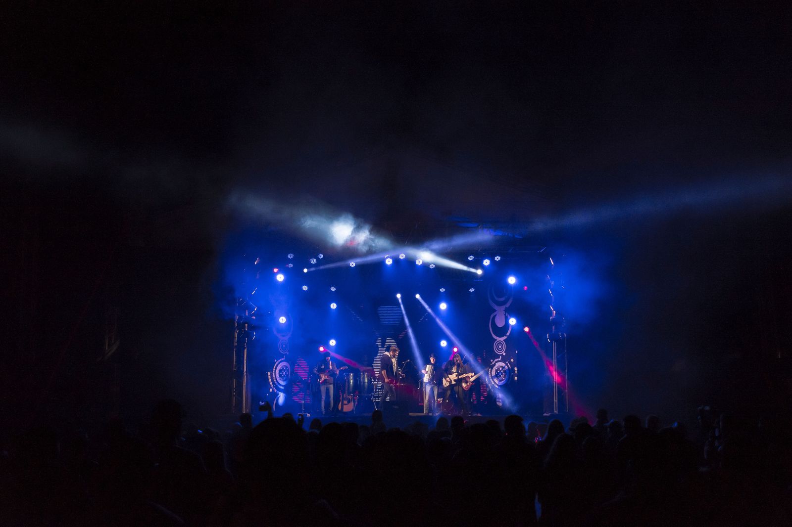 A folk festival stage and crowd in a lakeside park on a summer evening