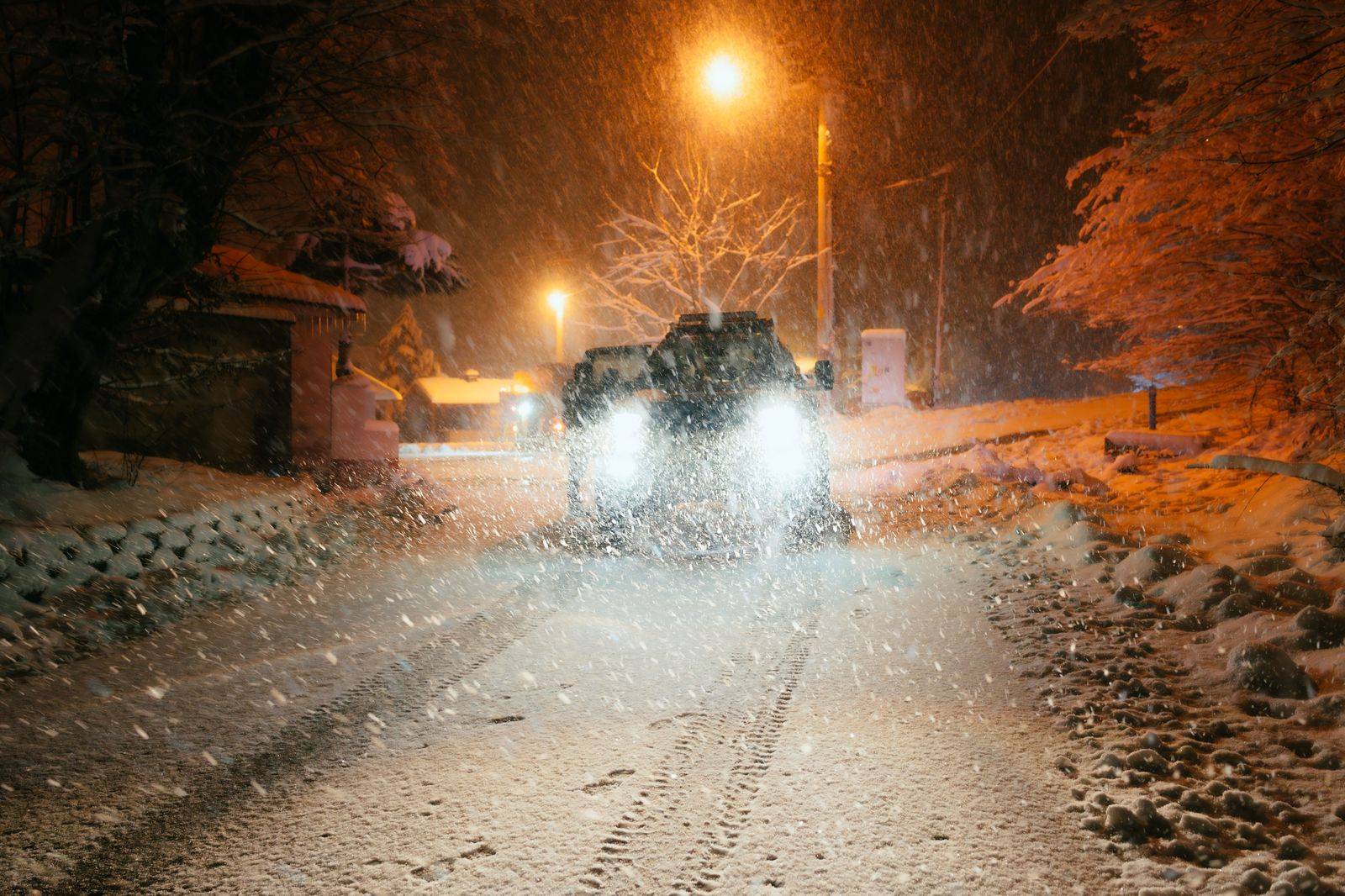 Black car driving carefully on a snowy road in winter near Toronto