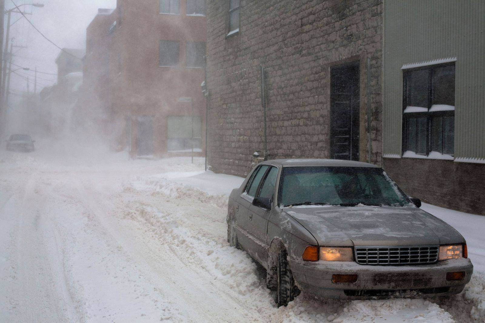 A black sedan on a downtown Toronto street in winter, heading to the AutoShow