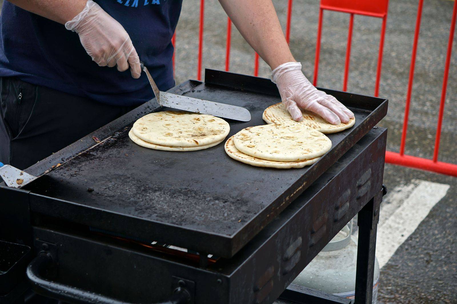 Greek grills and street food stalls line a closed city street during a summer festival