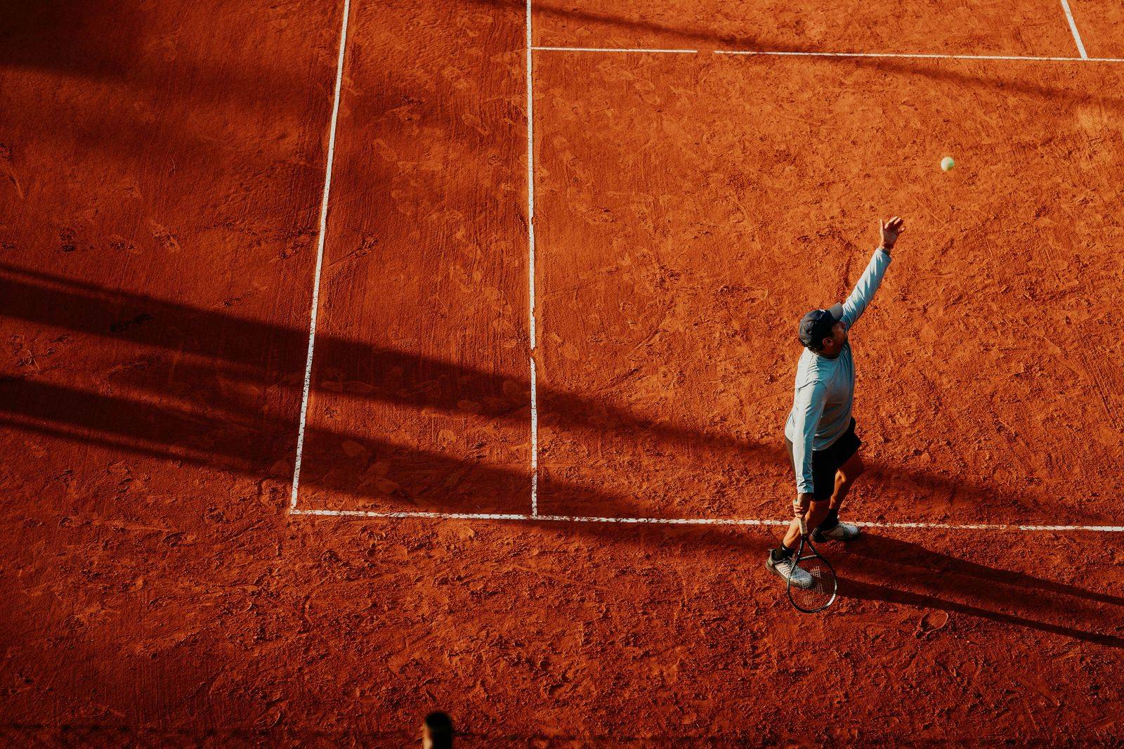 Player serving on a hard court during a night session