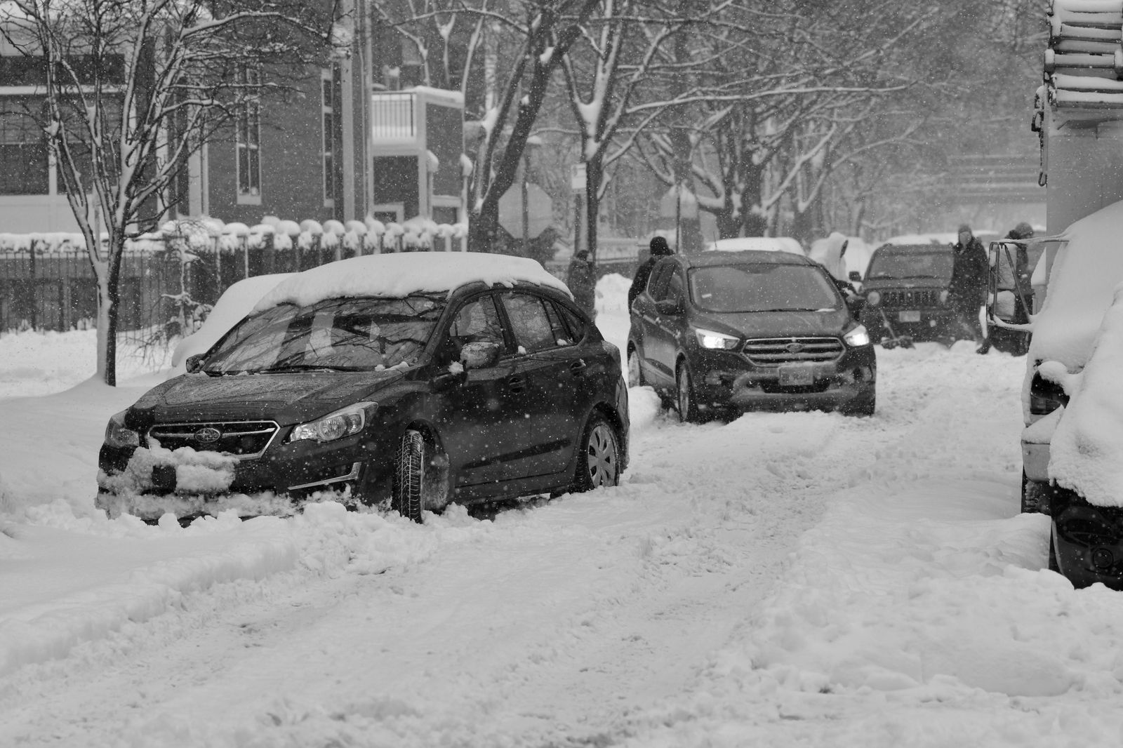 A black sedan waits on a snowy Toronto street
