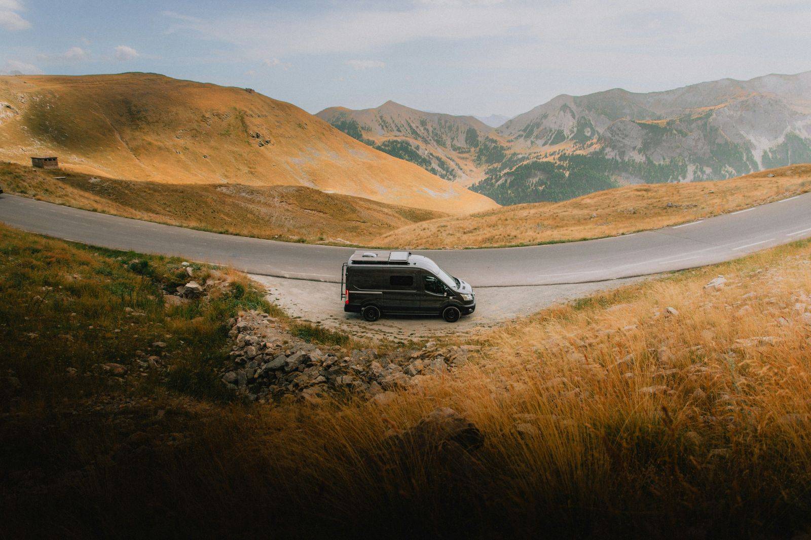 A black Sprinter van on a country road in summer
