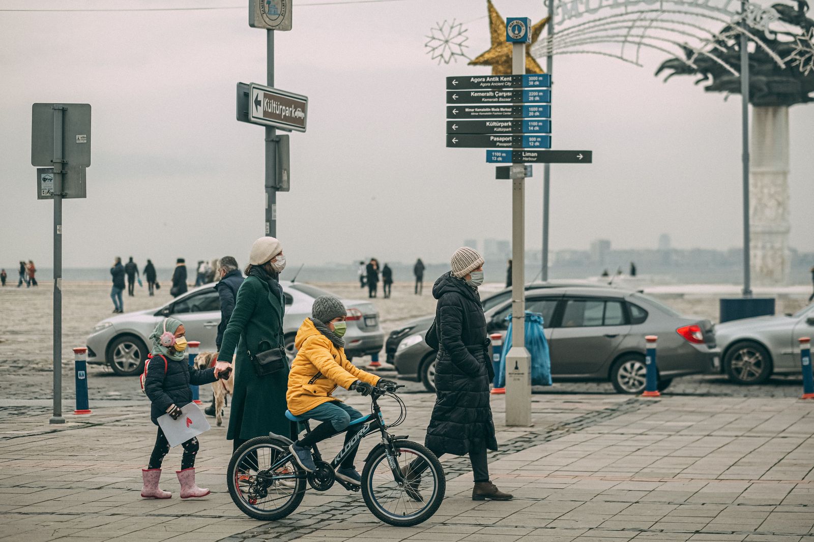 A family in winter coats walks to the curb ahead of the Santa Claus Parade