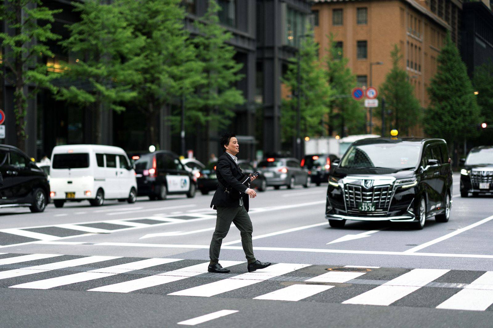 A pilot with a flight bag walking to a waiting chauffeured car after landing