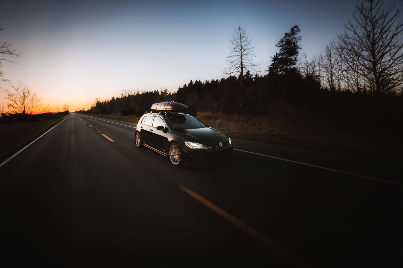 A black sedan on Highway 401 at dusk heading east toward Toronto