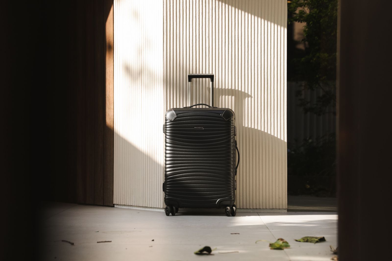 Chauffeur loading a suitcase into the back of a black SUV at an airport