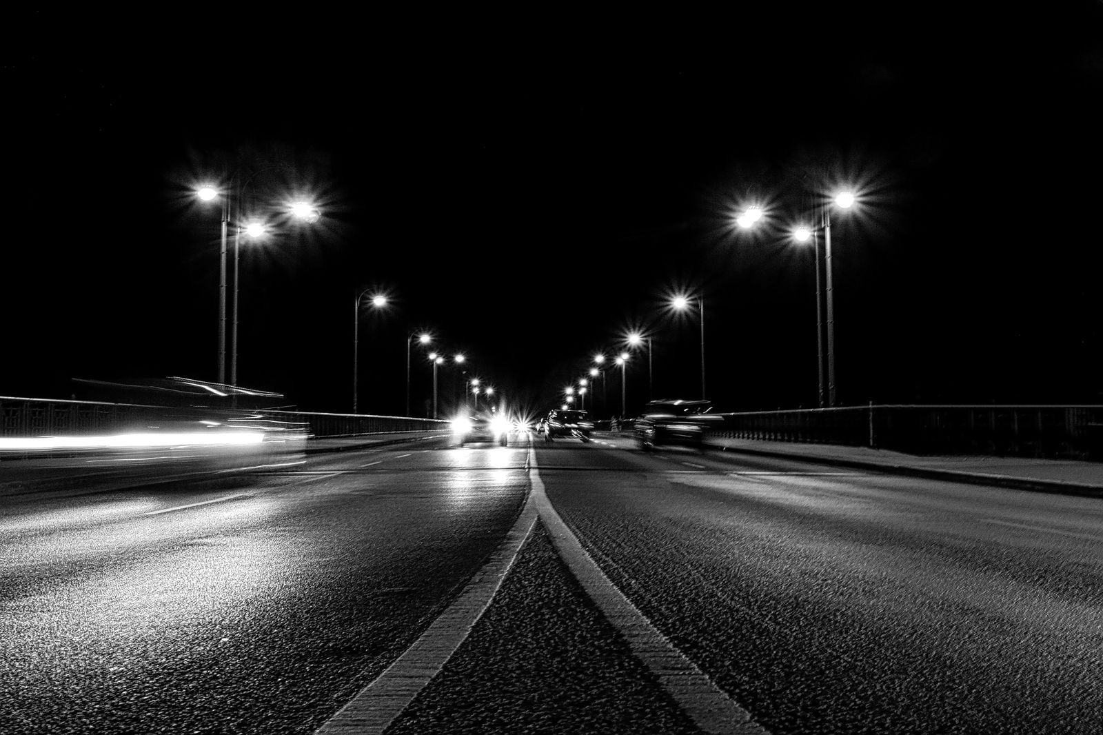 Black sedan on a highway at night heading toward an airport
