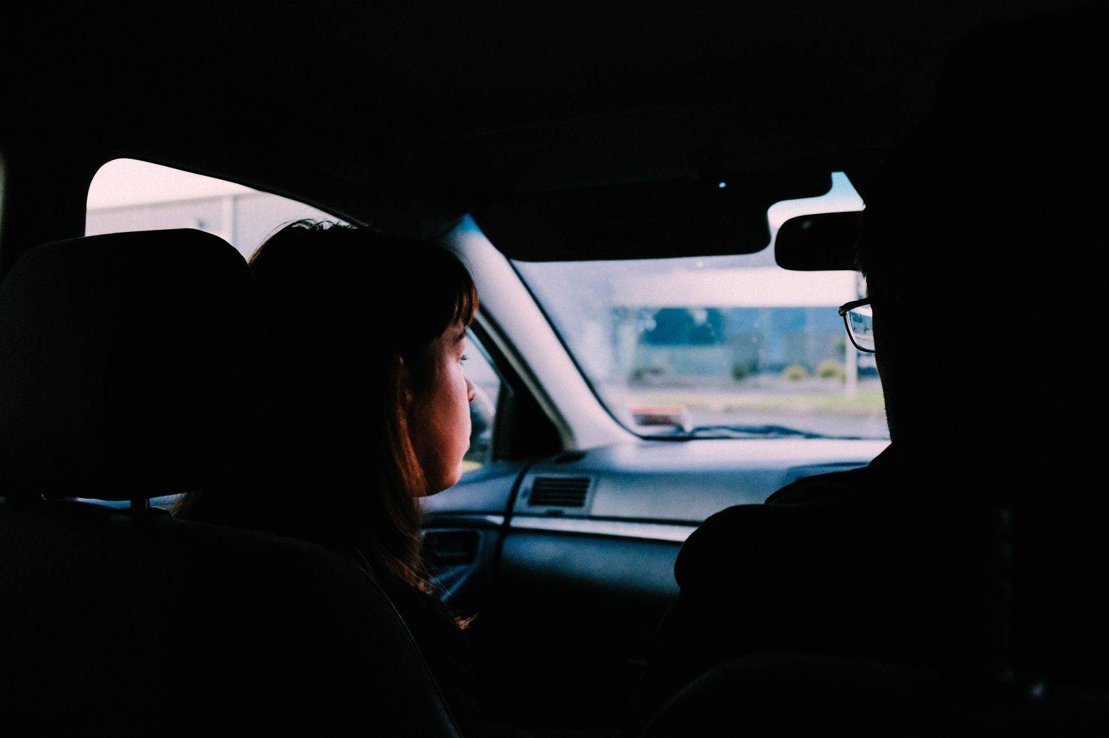 A passenger relaxing in the back seat of a black car on an evening ride in Toronto