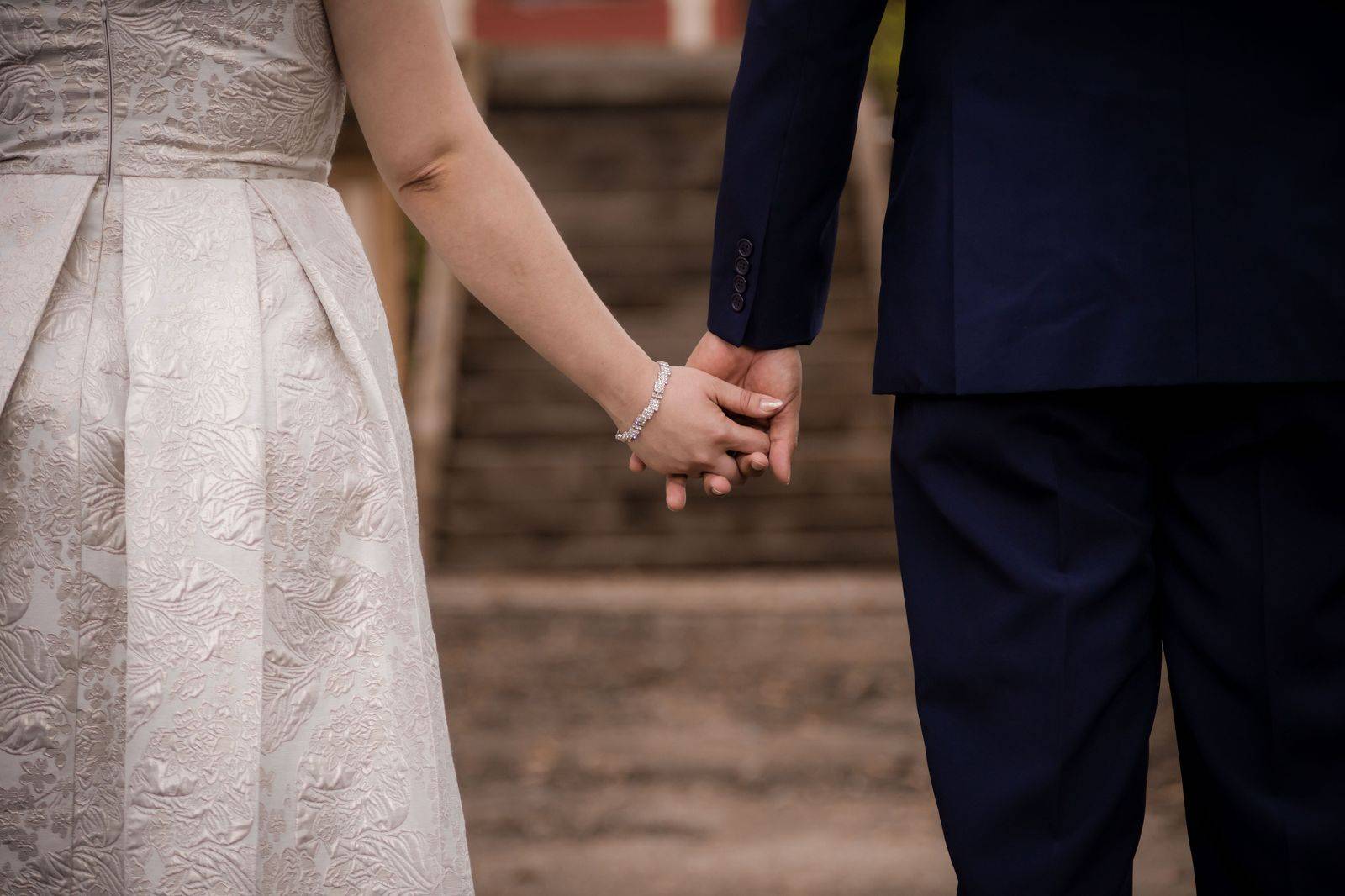 A wedding couple poses for photos in a brick laneway beside their car