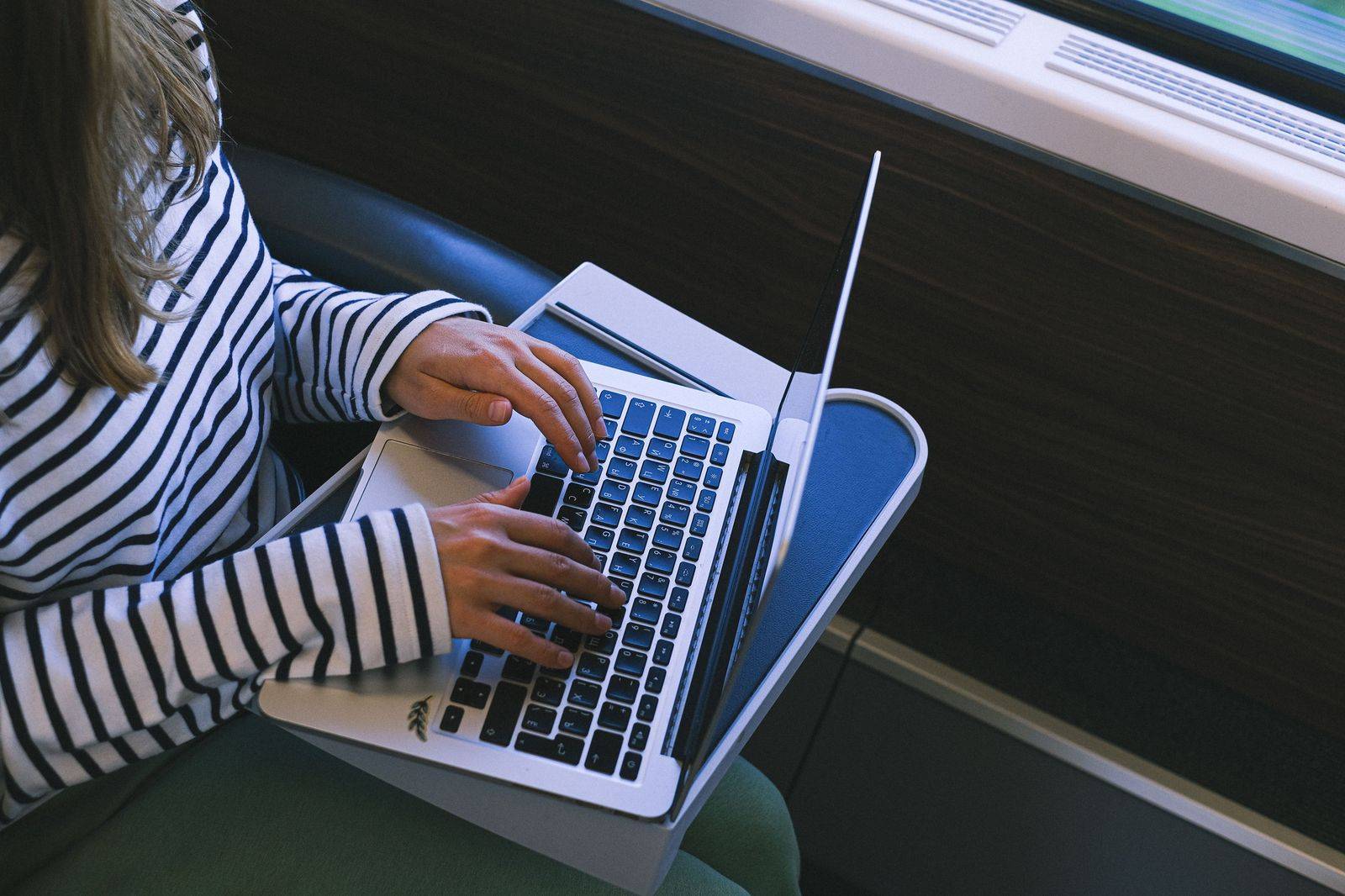 A business traveller working on a laptop in the back seat of a car