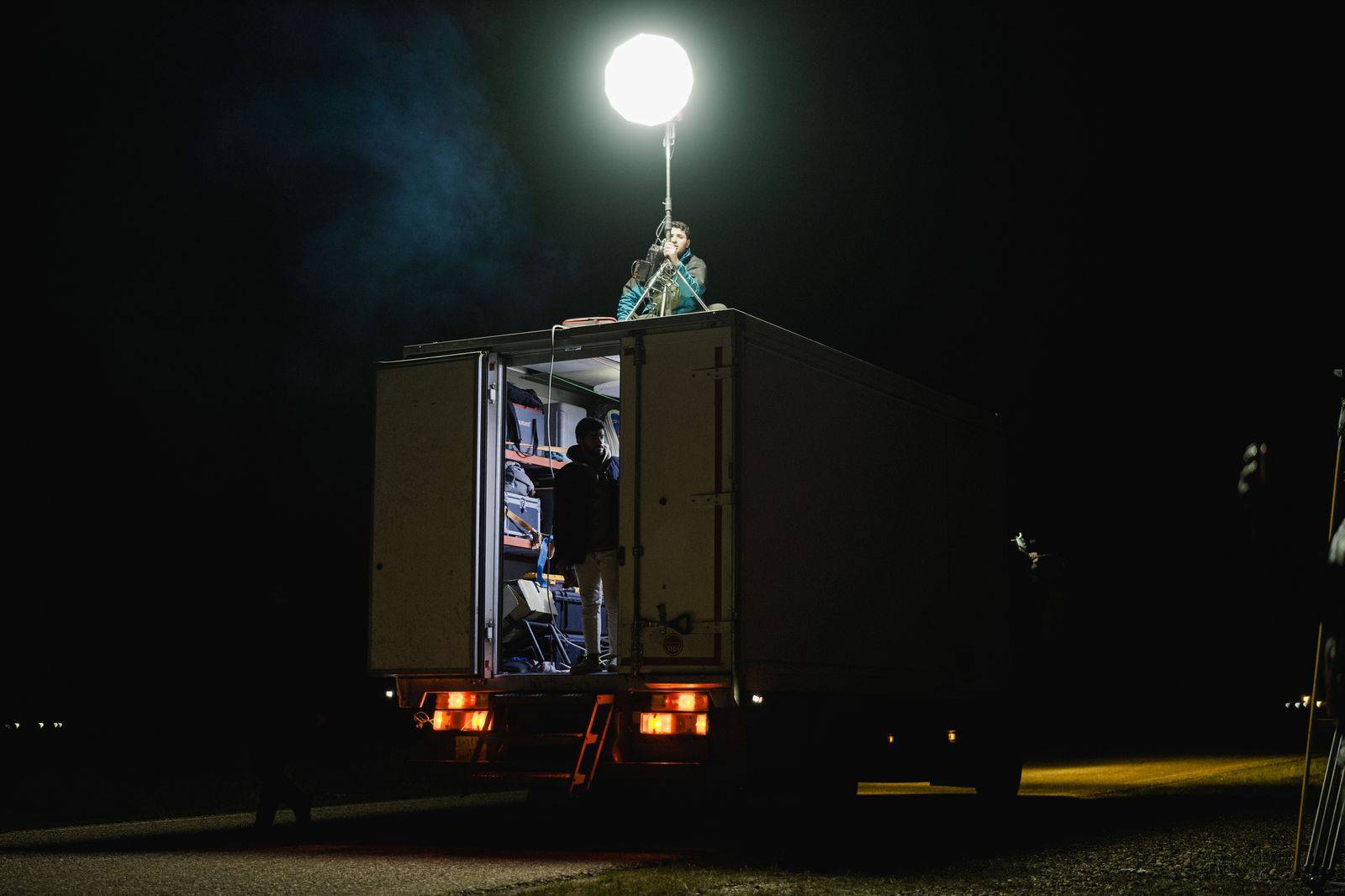 Lights and equipment on a night location shoot, where cast cars and crew Sprinters hold close to set
