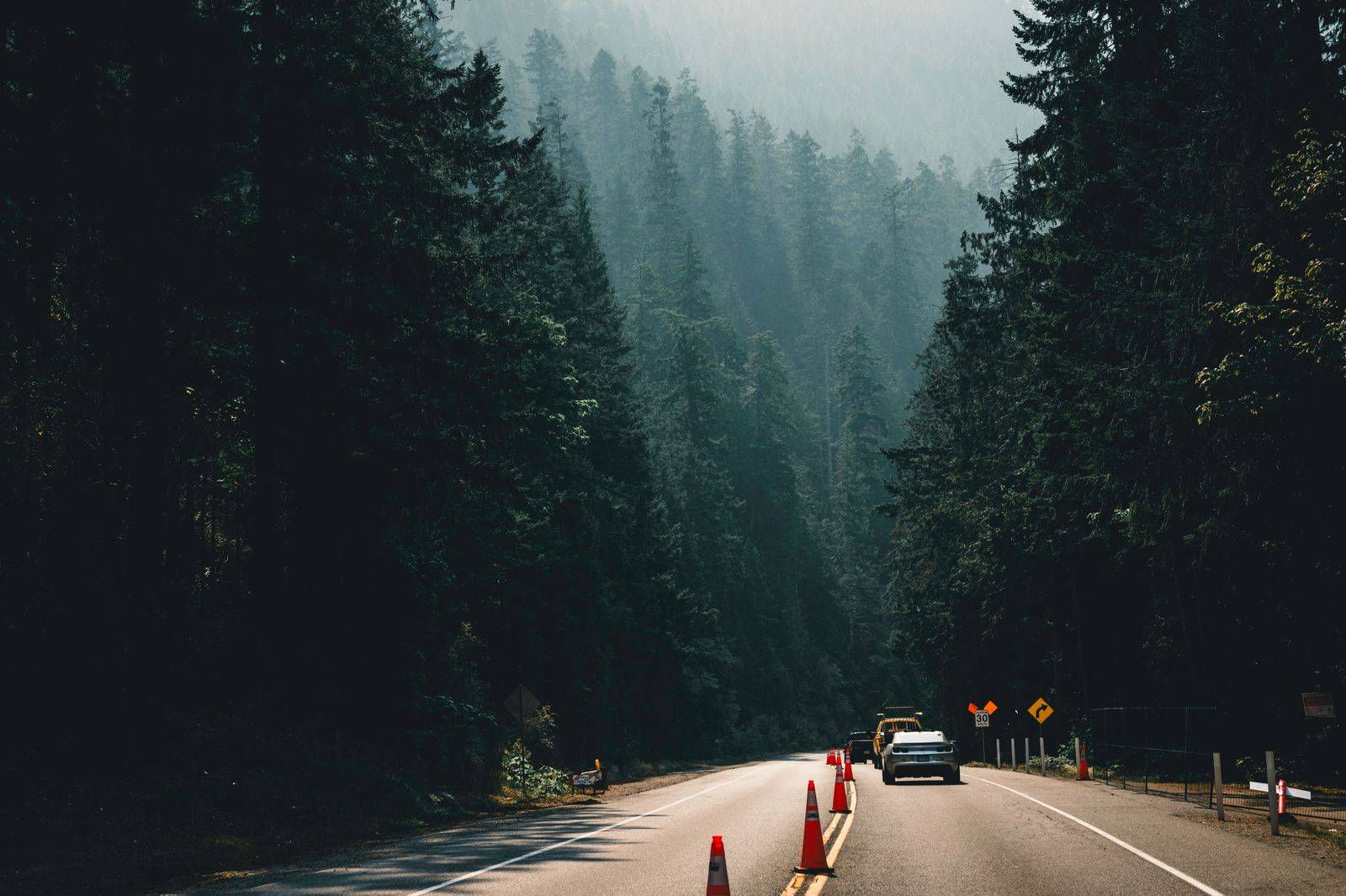 A black sedan on a divided highway through northern Ontario forest beside a lake