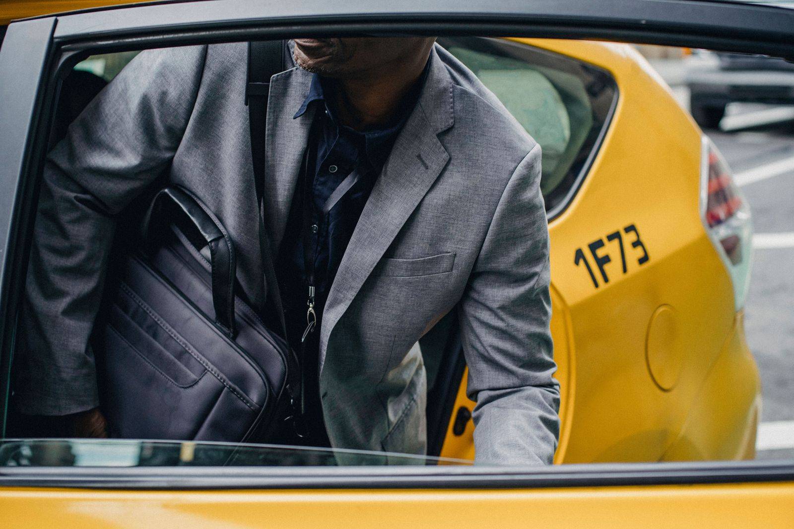 A business traveller with a briefcase stepping out of a black car at an office entrance