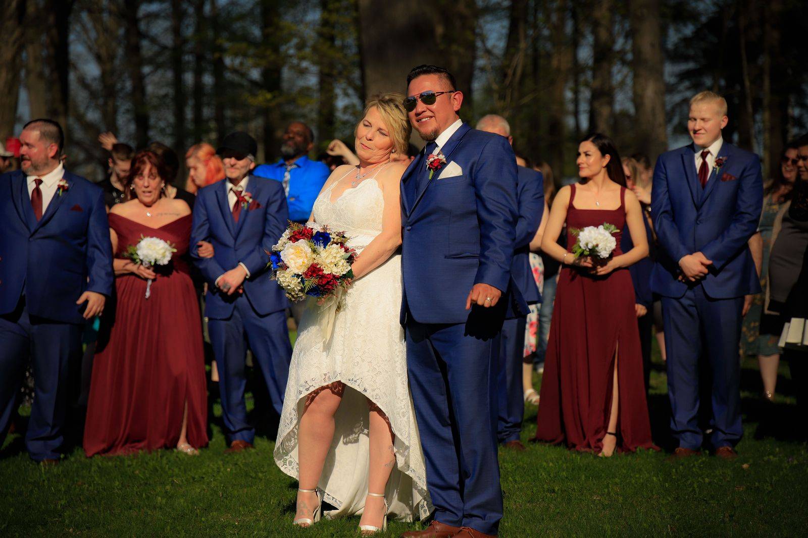 A wedding party gathers beside a limousine before the ceremony