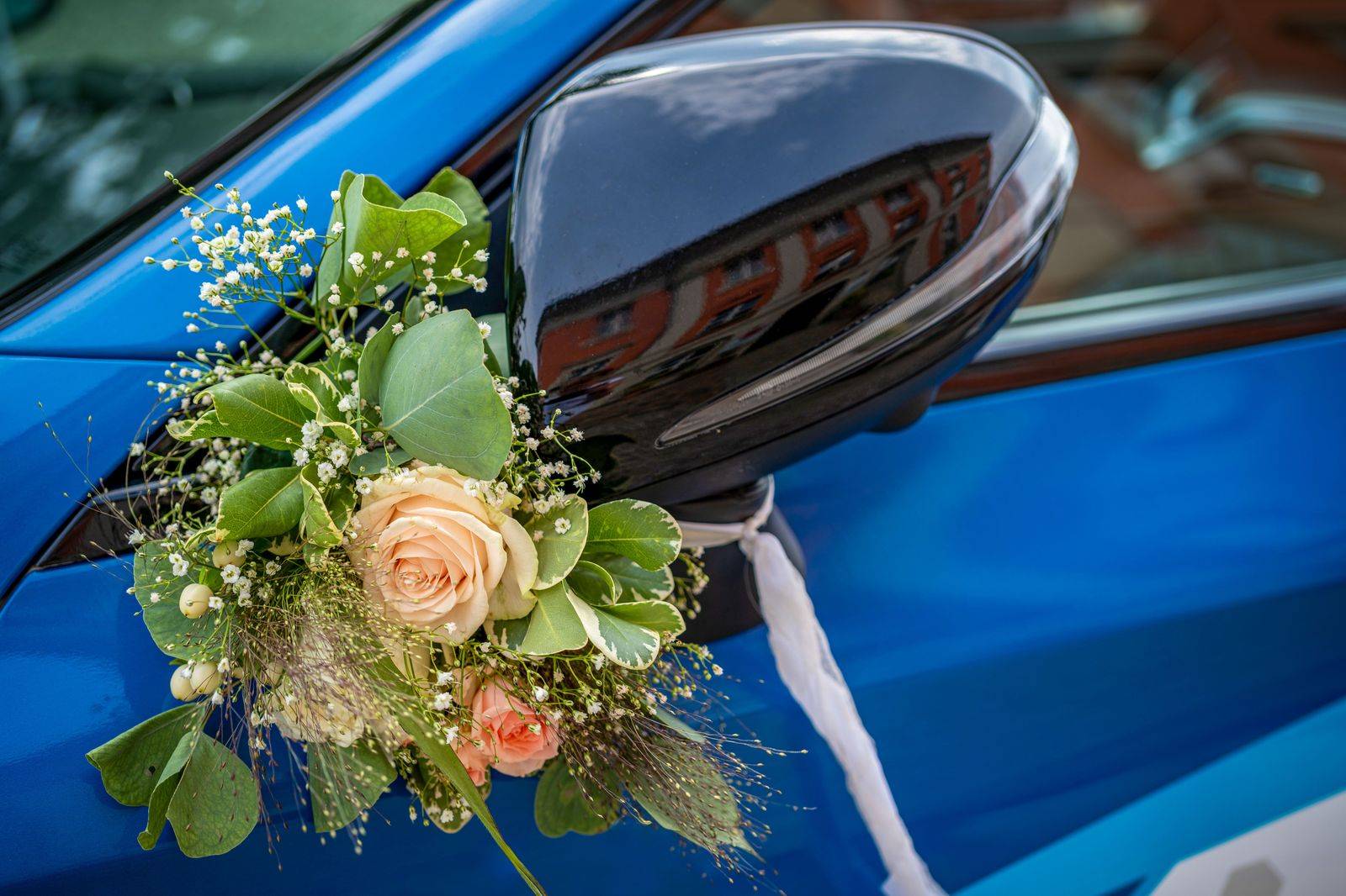 A decorated wedding car with ribbon and flowers waits for the couple