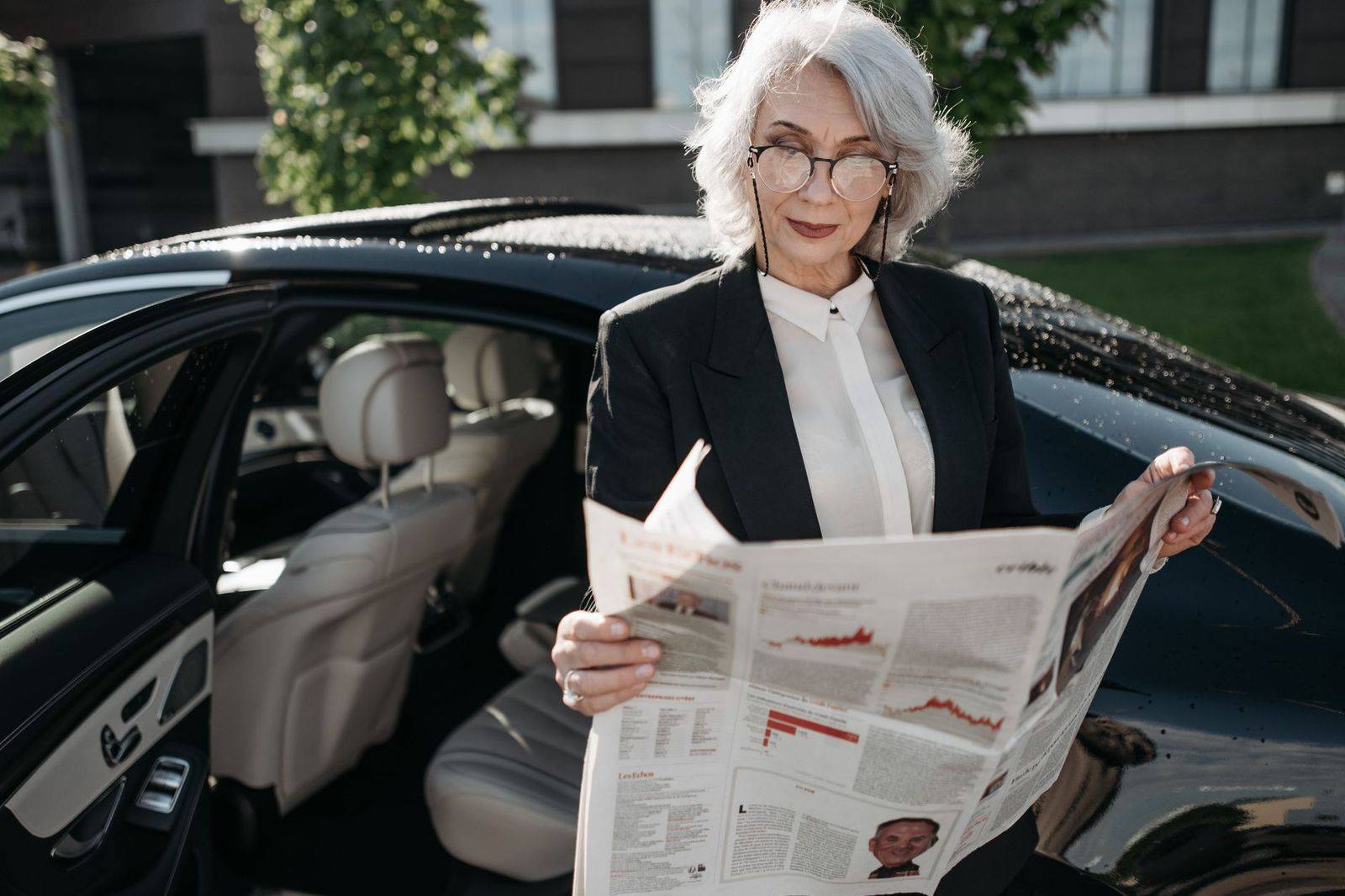 A chauffeur holding the rear door of a black sedan before the drive from Boston to Toronto