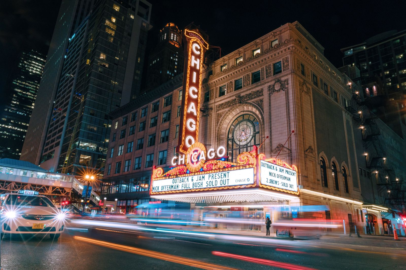Theatre lights glowing on a downtown street before an evening performance